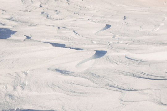 Sunlit wind-sculpted snow texture with soft winter shadows