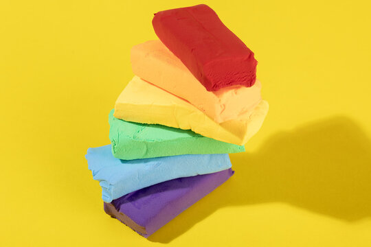 Colorful modeling clay stack on yellow background still life