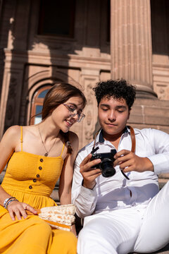 Mexican teenagers review camera photos outside historic building