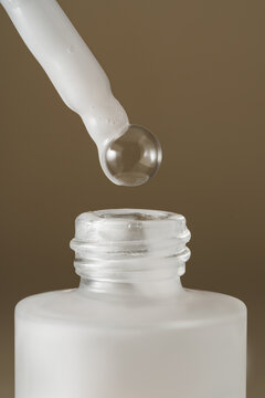 Clear serum dropper above cosmetic bottle