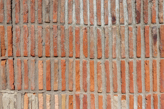 Vintage red brick wall texture with narrow vertical brickwork pattern