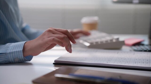 Business professional using a white keyboard beside printed accounting reports, illustrating financial data processing, bookkeeping workflow, digital administration, and everyday office productivity.