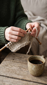 Woman Hand Knitting Wool Scarf Beside Coffee Mug