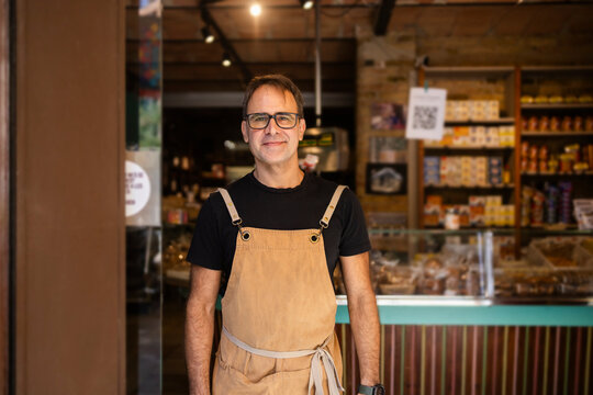 Smiling shop owner in gourmet food store entrance