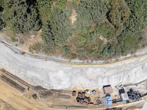 Aerial view of road construction beside dense woodland