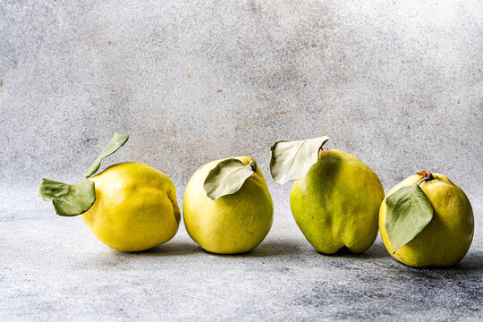 Ripe quince fruit with leaves on a gray surface