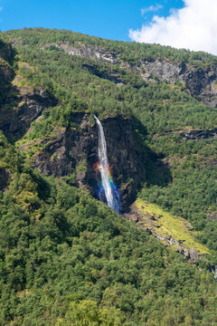 Waterfall and rainbow in Norway mountain forest landscape