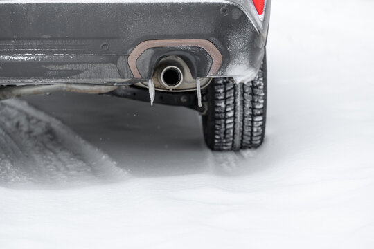 Snow-covered car exhaust pipe and undercarriage close-up