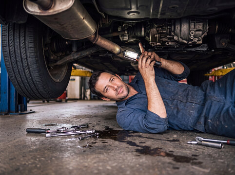 Auto mechanic repair vehicle underside in service garage