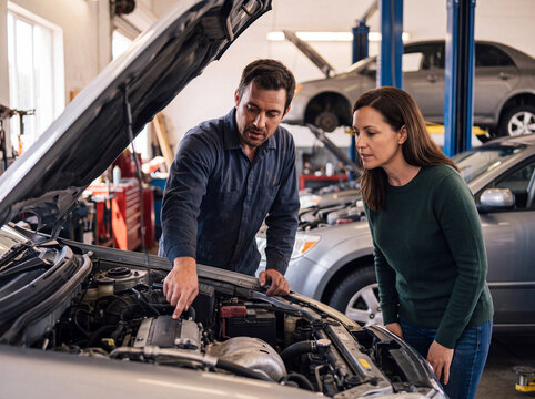 Auto mechanic explain engine repair to female customer