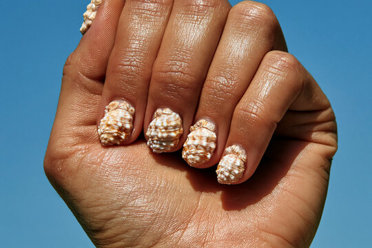Hands with seashell nail art against blue background
