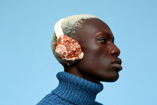 Surreal shell headphones on human face against blue sky