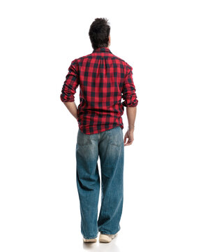 Back view of casual man walking in loose jeans