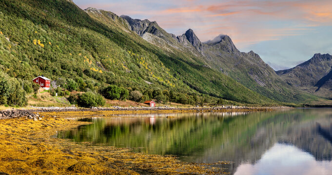 Scenic autumn landscape at Olderfjord with red cabin and mountain reflections in the Lofoten Islands, Norway