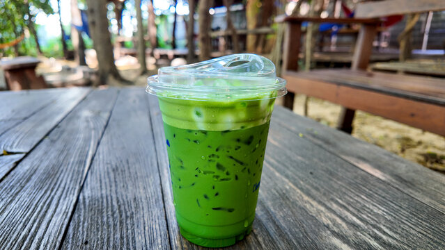 Fresh Green Matcha Drink in a Clear Cup on Wooden Table Outdoors