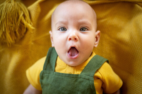 Surprised Baby Lying on Yellow Blanket Autumn Concept