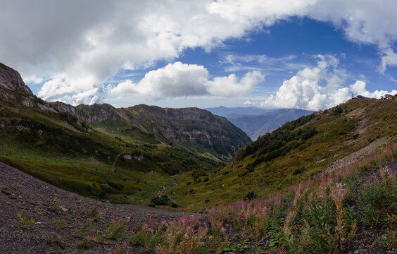 Deep mountain valley with grassy slopes and fluffy clouds