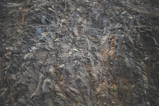 Close-up texture of dark layered rock face with cracks