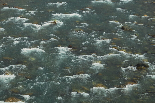 Mountain river with visible stones and white rapids abstract background