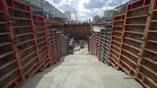 Wooden formwork walls line wide concrete staircase in deep trench. Large scale engineering project demonstrates steady site progress