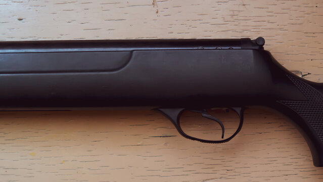 Gun trigger close up. air rifle lying on a light wooden surface