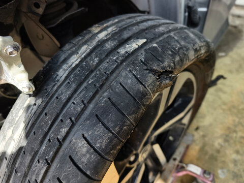 Damaged car tire with a torn tread and visible wheel rim