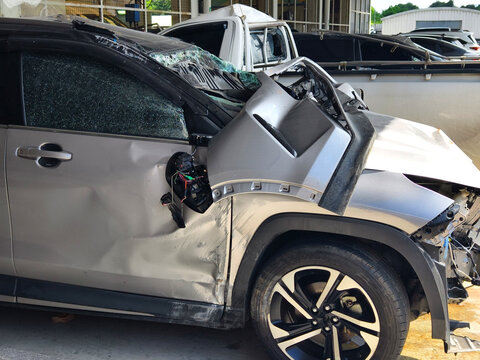Silver car with heavy collision damage parked inside repair garage