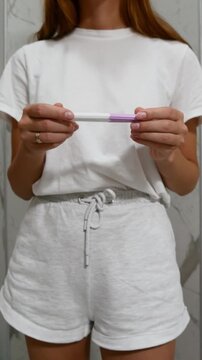 Close-up of woman holding pregnancy test and checking result at home, pregnancy testing and family planning concept