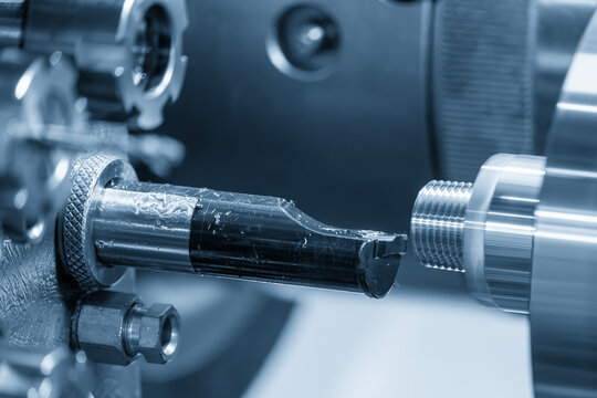 Outside thread making process on steel pipe parts using a CNC lathe machine in a blue tone scene