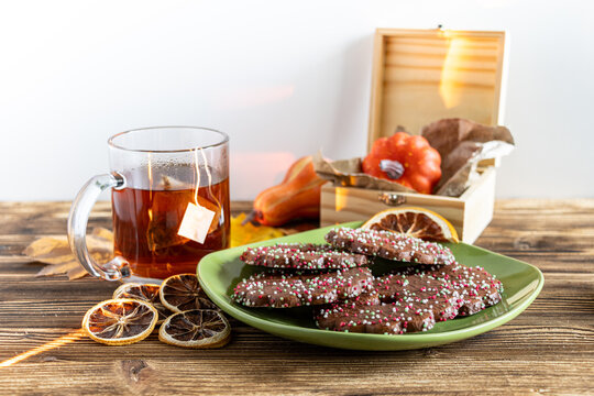 Cozy autumn still life with chocolate cookies, tea, dried citrus, and a small decorative pumpkin   