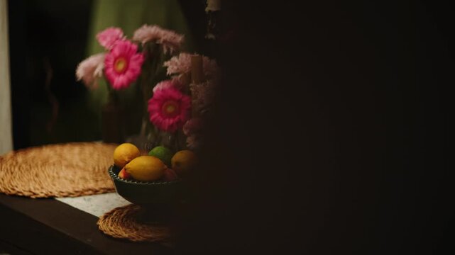 Beautiful dinner table with pink flowers and fresh fruit in vases at night
