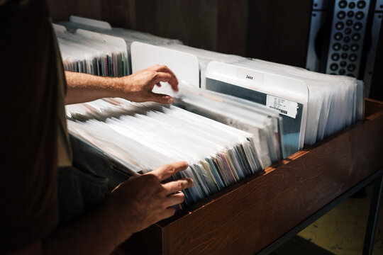 Vinyl collector browsing records at music shop, embracing retro analog culture, nostalgia and slow living through physical music discovery.