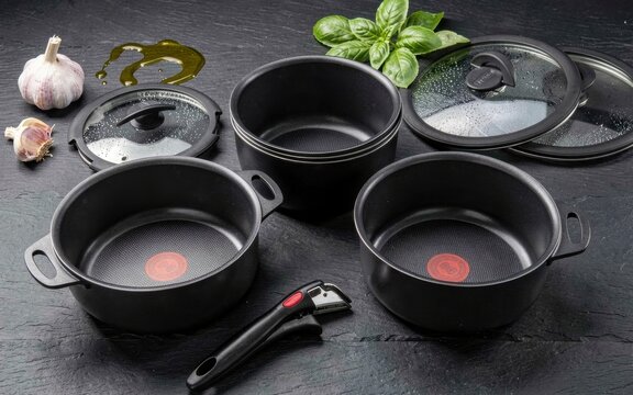 Black nonstick cookware set with glass lids on a dark background