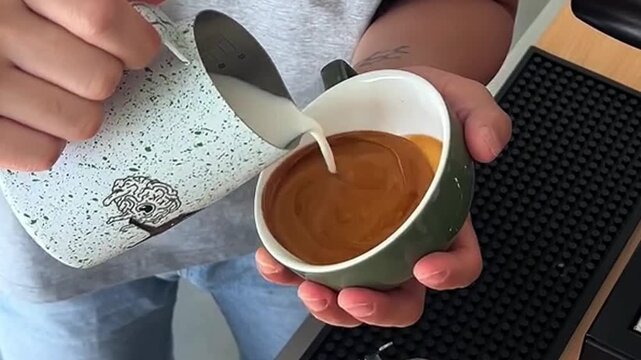 Barista holding a cup of freshly brewed coffee with intricate rosetta and tulip latte art pattern