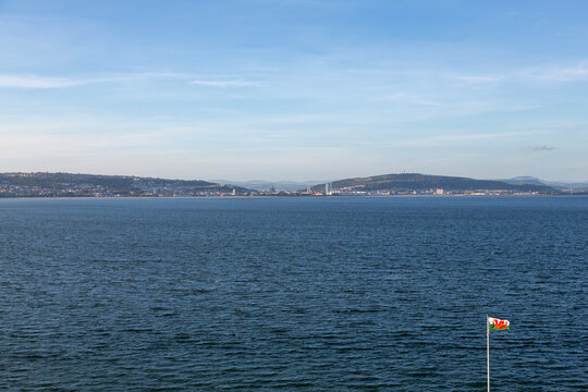 View of Swansea from Mumbles Pier with a Welsh flag fluttering in the foreground