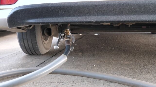 Close up of connecting gas refueling hose to car underbody