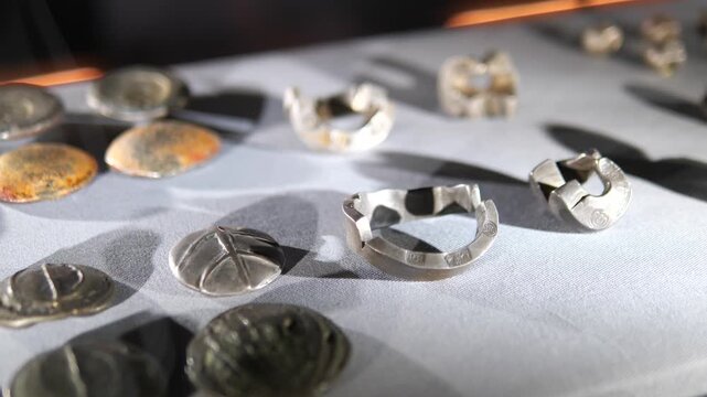 Close up of ancient silver coins and jewelry artifacts on display