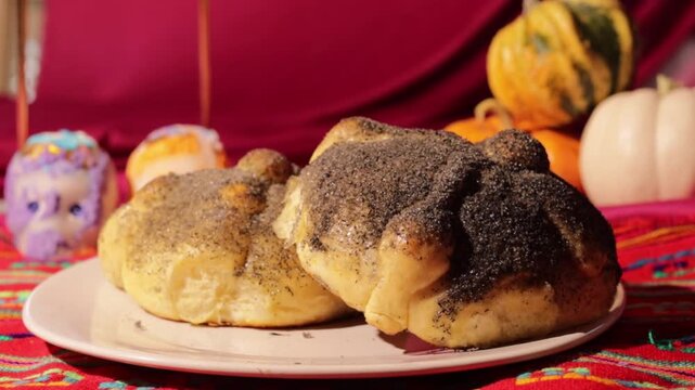 Traditional pan de muerto with sugar skulls and pumpkins on a mexican day of the dead ofrenda altar with a red and magenta background celebrating dia de los muertos