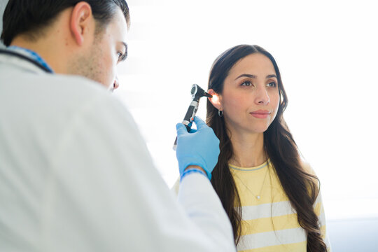 Medical professional examining female patient's ear with an otoscope during a medical check-up for hearing health and wellness