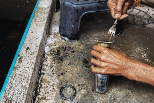 Clogged sink pipe in hands ,A plumber cleans a clogged siphon pipe of a sink in the kitchen. Clogged rusty water trap siphon and drainage pipe cleaning. Home plumbing maintenance service. DIY concept