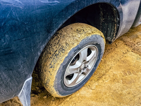 Four wheel drive pickup truck wheel cover with thick mud while driving on rough, muddy dirt road, Off road capability and adventure travel. Dirty car tire cover in mud driving on muddy off road track.