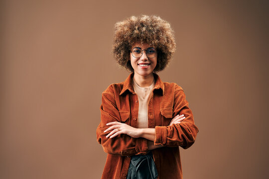 Confident smiling woman with curly hair and glasses.
