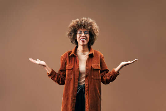 Smiling woman with open hands on brown background.
