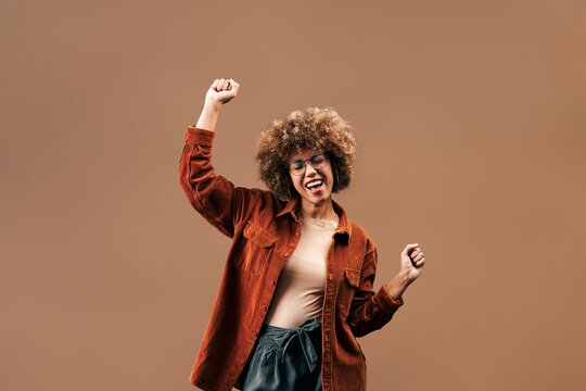 Cheerful woman dancing with raised fists.
