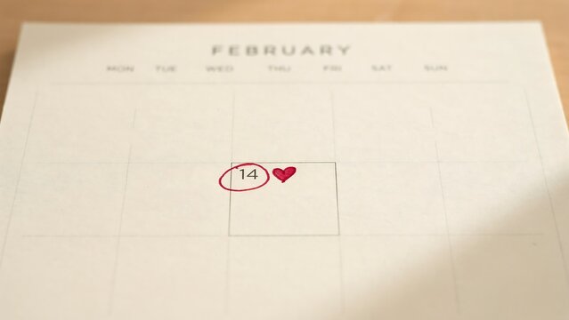 February calendar page with the 14th circled in red ink and a small red heart drawn next to it on a white background