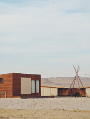 Wooden cabins and a teepee frame in the desert © hos8