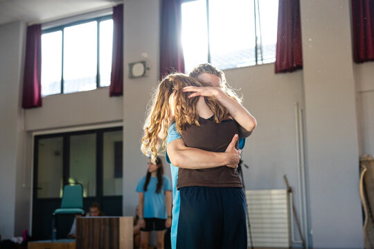 Dancers embrace during rehearsal