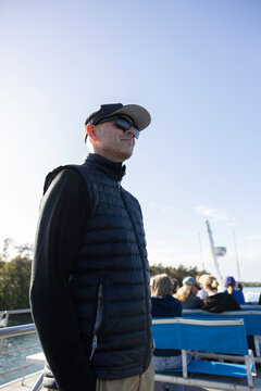 Man standing on a boat with blue sky behind in Australia
