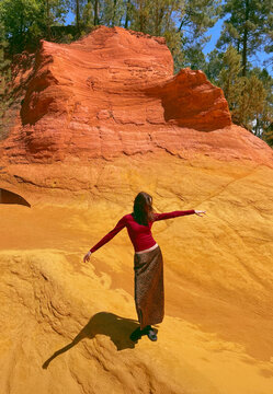Woman standing with arms extended in red orange sandstone landscape