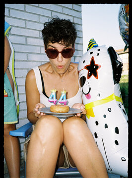 Woman blowing out 44th birthday donut candles